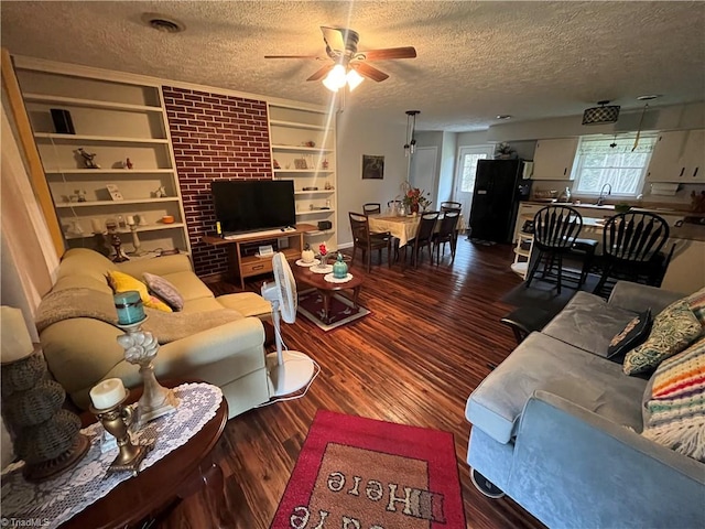 living room with ceiling fan, a textured ceiling, and dark hardwood / wood-style floors