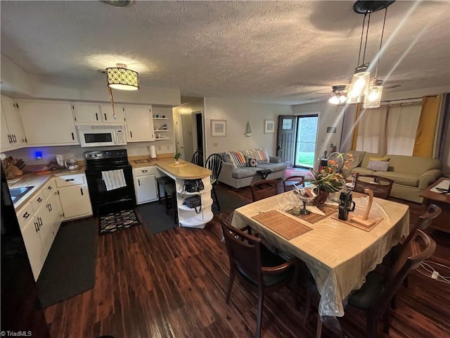 dining area featuring dark wood-type flooring, a textured ceiling, and ceiling fan