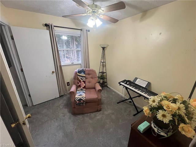 sitting room with a textured ceiling, dark carpet, and ceiling fan