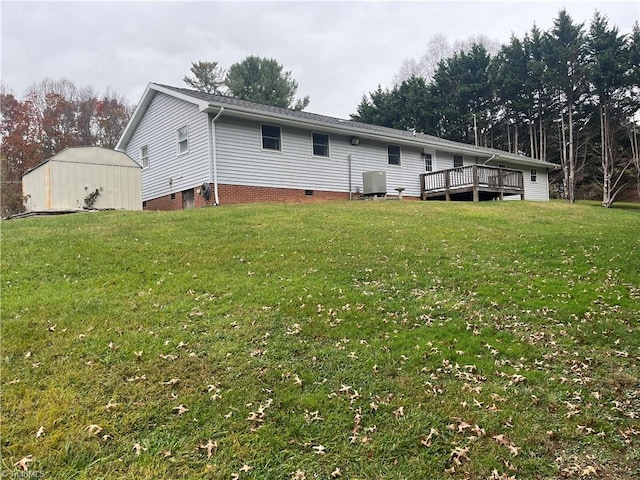 rear view of property featuring a lawn, a wooden deck, and central AC