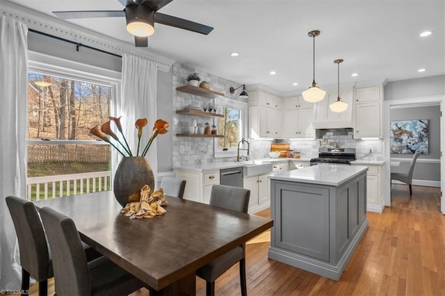 kitchen with light wood finished floors, a kitchen island, light countertops, appliances with stainless steel finishes, and white cabinets