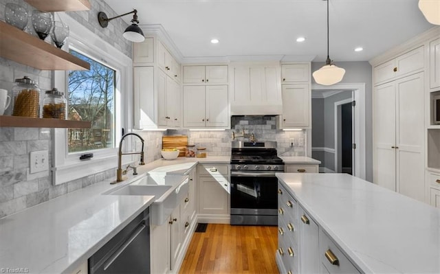 kitchen with tasteful backsplash, open shelves, decorative light fixtures, stainless steel appliances, and a sink