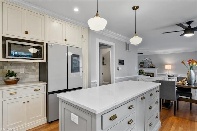 kitchen featuring stainless steel microwave, visible vents, crown molding, open floor plan, and refrigerator