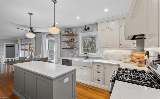 kitchen featuring tasteful backsplash, a kitchen island, light countertops, range hood, and light wood-style floors