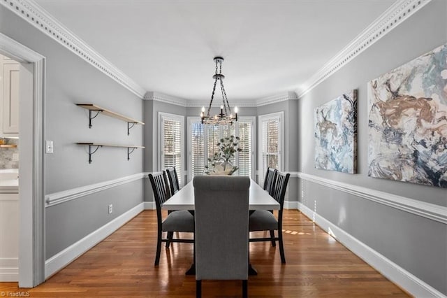 dining space with crown molding, wood finished floors, baseboards, and a chandelier