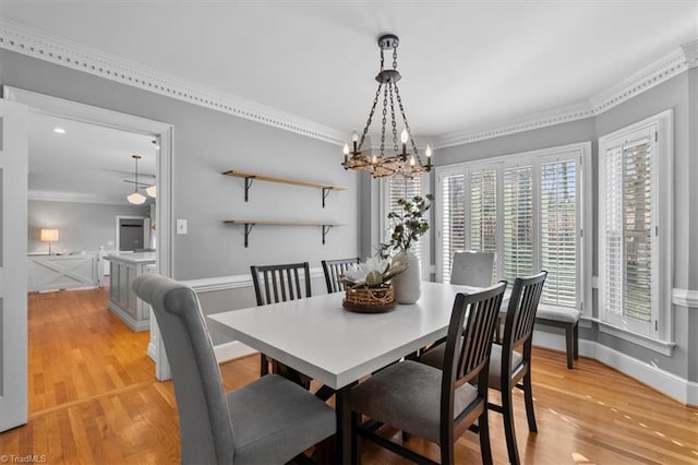 dining room featuring baseboards, a notable chandelier, crown molding, and light wood finished floors