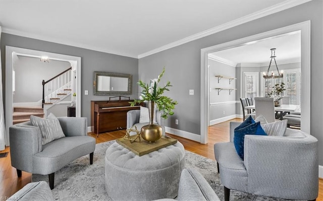 living room featuring a notable chandelier, ornamental molding, wood finished floors, baseboards, and stairs