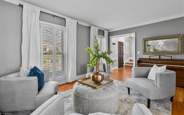 sitting room featuring stairs, crown molding, wood finished floors, and baseboards