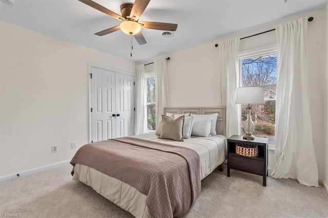 bedroom featuring multiple windows, light carpet, baseboards, and ceiling fan