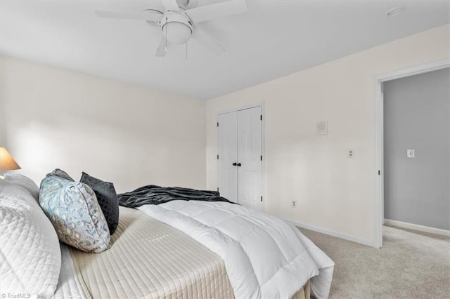 bedroom with light colored carpet, baseboards, a closet, and ceiling fan