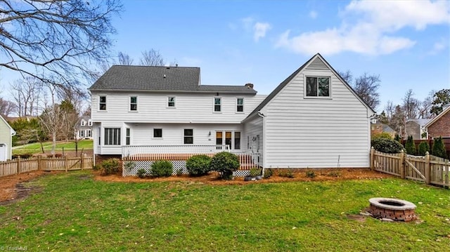 back of property featuring a wooden deck, a yard, an outdoor fire pit, and a fenced backyard