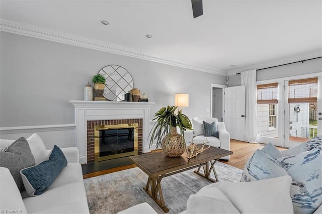 living room with wood finished floors, a fireplace, and ornamental molding