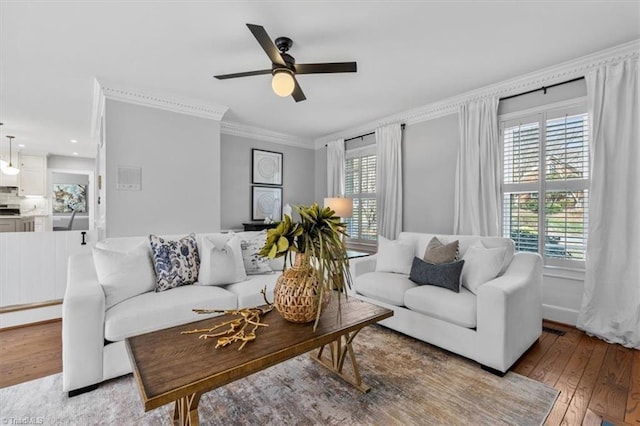 living room featuring ceiling fan, plenty of natural light, ornamental molding, and light wood finished floors