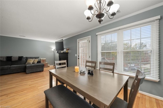 dining room with ornamental molding, a notable chandelier, and light wood-type flooring