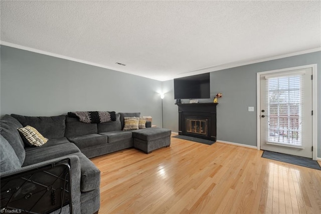 living room featuring crown molding, wood-type flooring, and a textured ceiling