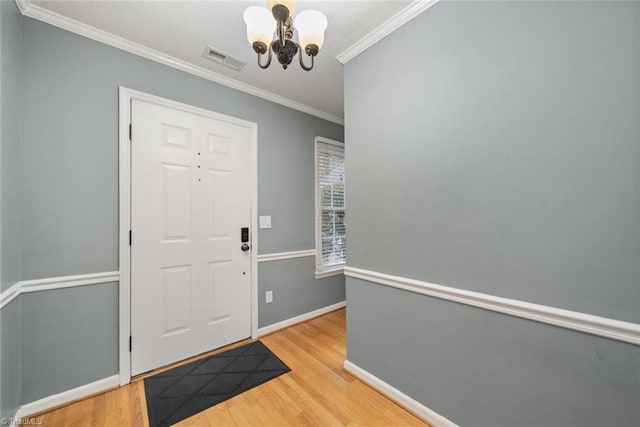 foyer with an inviting chandelier, light hardwood / wood-style flooring, and crown molding