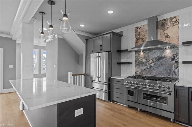 kitchen with wall chimney range hood, ornamental molding, high quality appliances, and light wood-type flooring