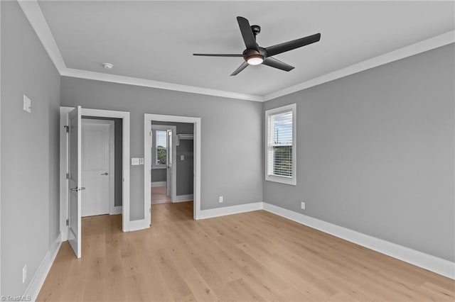 unfurnished bedroom featuring ornamental molding, multiple windows, light wood-type flooring, and ceiling fan