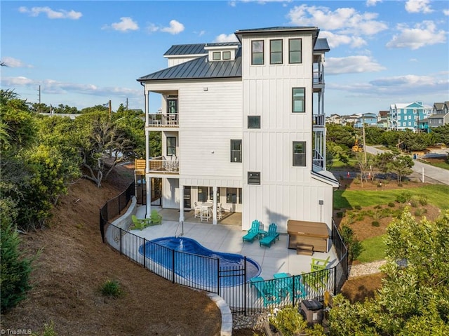 back of house with a balcony, a covered pool, and a patio