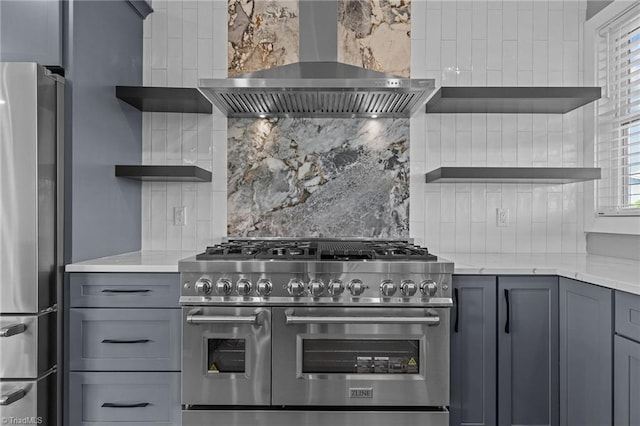 kitchen with wall chimney range hood, gray cabinetry, stainless steel appliances, and backsplash