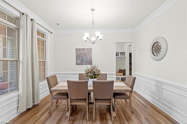 dining space with light wood-type flooring, crown molding, and a chandelier