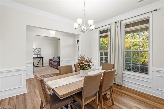 dining space featuring a chandelier, light hardwood / wood-style floors, and ornamental molding