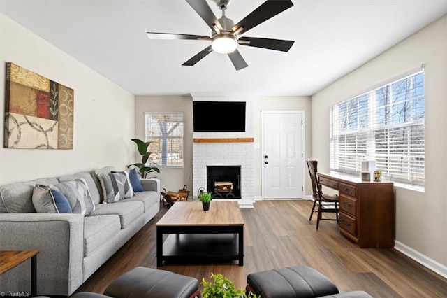 living room featuring dark hardwood / wood-style flooring, a brick fireplace, and ceiling fan