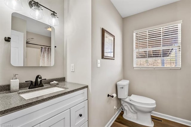 bathroom featuring hardwood / wood-style flooring, vanity, walk in shower, and toilet