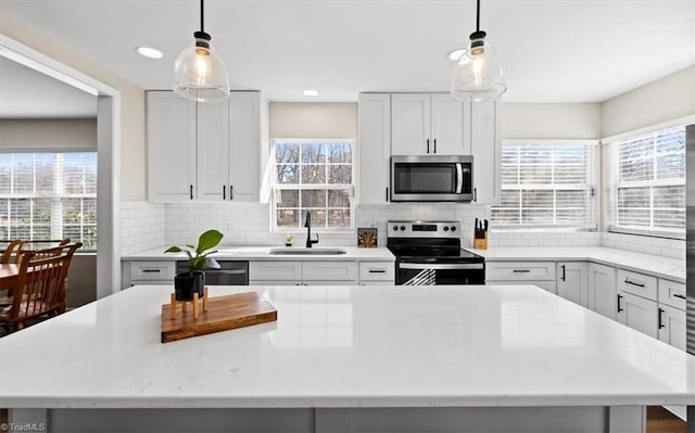 kitchen with stainless steel appliances, hanging light fixtures, sink, and a kitchen island