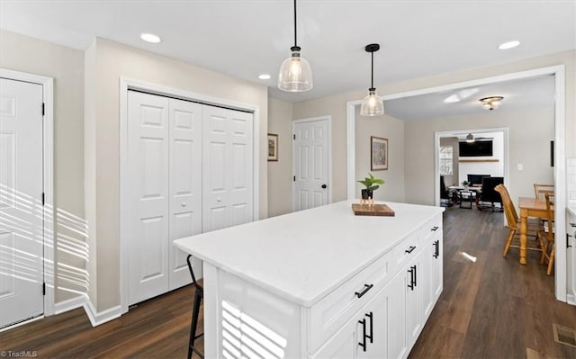 kitchen featuring pendant lighting, dark hardwood / wood-style flooring, a center island, and white cabinets