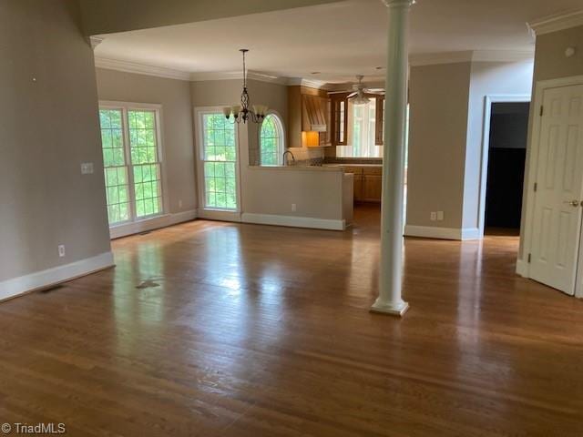 unfurnished living room with hardwood / wood-style floors, ceiling fan with notable chandelier, and ornamental molding