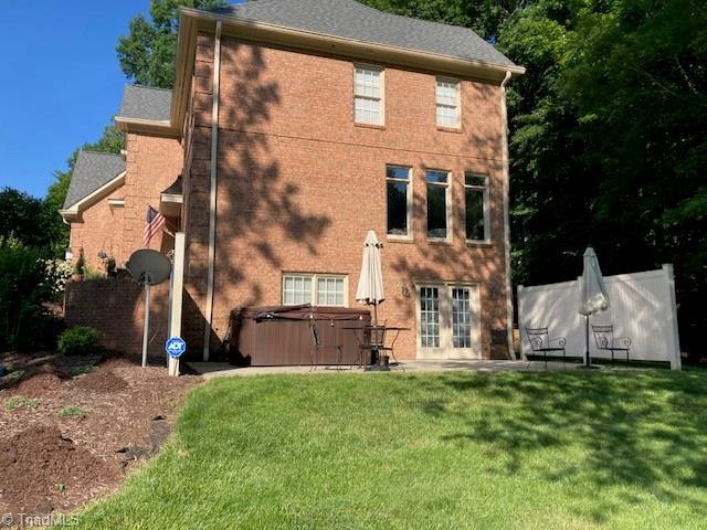 rear view of house with a yard and a hot tub