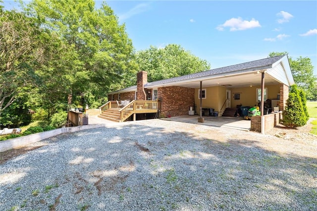8194 Brotherstwo Rd, Colfax, NC 27235 - back of property featuring a chimney, gravel driveway, an attached carport, and stairs