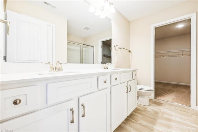 bathroom featuring vanity, a shower with shower door, and toilet