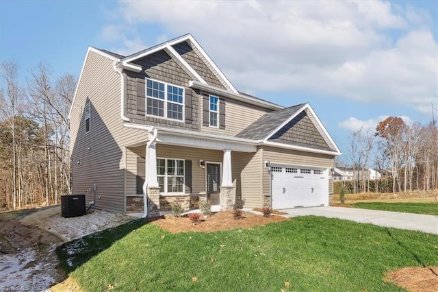 craftsman house with covered porch, a garage, cooling unit, and a front yard