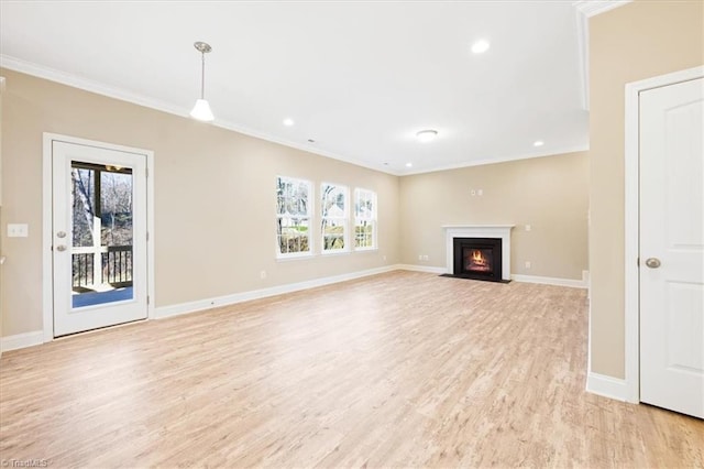 unfurnished living room featuring a healthy amount of sunlight, light hardwood / wood-style floors, and ornamental molding