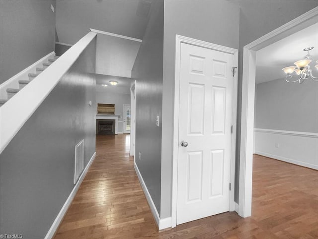 hallway featuring dark wood-style floors, visible vents, a chandelier, baseboards, and stairs