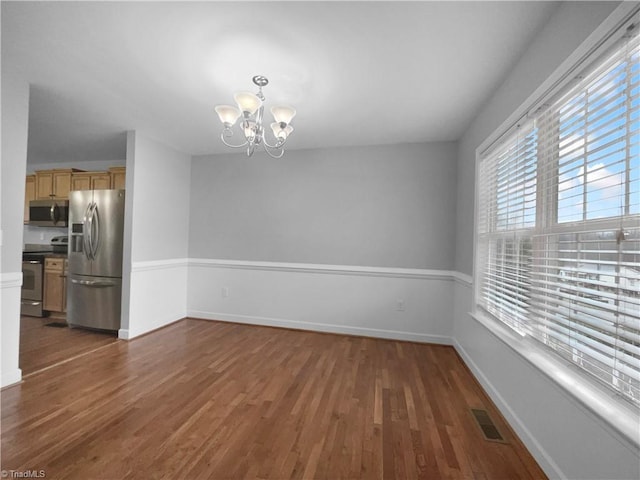 unfurnished dining area featuring visible vents, dark wood finished floors, baseboards, and an inviting chandelier