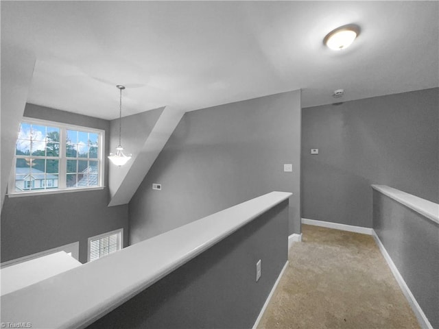 hall with baseboards, light colored carpet, and an upstairs landing