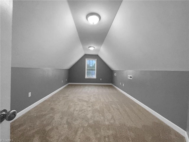 additional living space featuring carpet, visible vents, vaulted ceiling, and baseboards