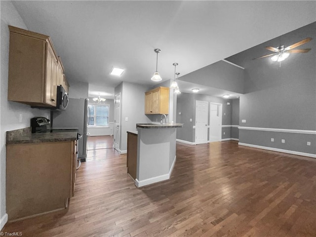 kitchen featuring dark countertops, open floor plan, dark wood-style flooring, decorative light fixtures, and stainless steel appliances