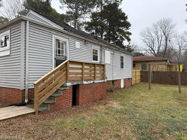 back of property featuring a deck and a lawn