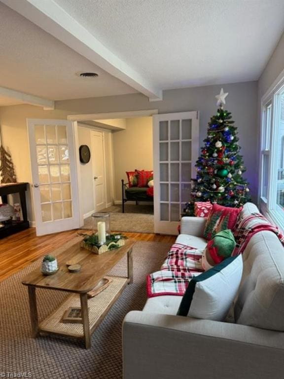 living room featuring wood-type flooring, french doors, and beam ceiling