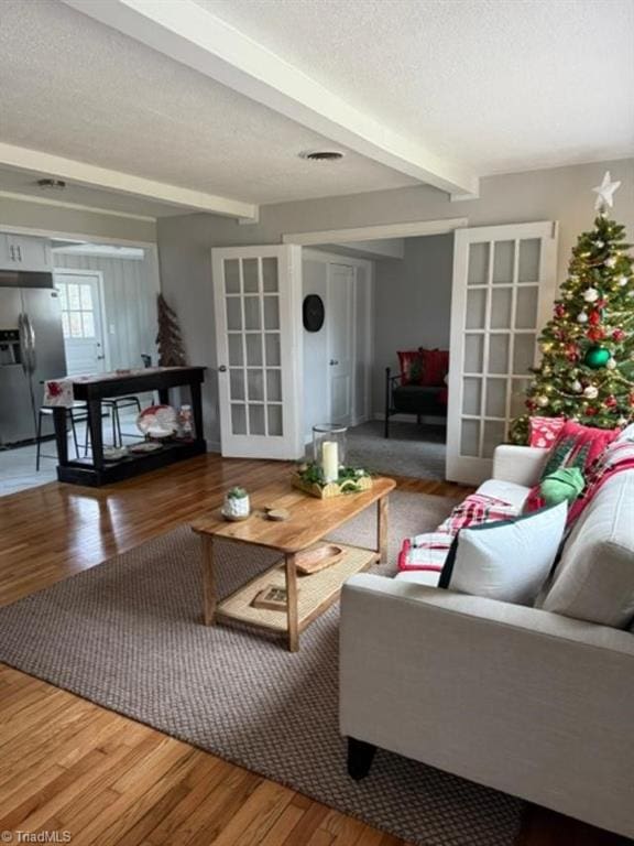 living room featuring beamed ceiling, wood-type flooring, and french doors