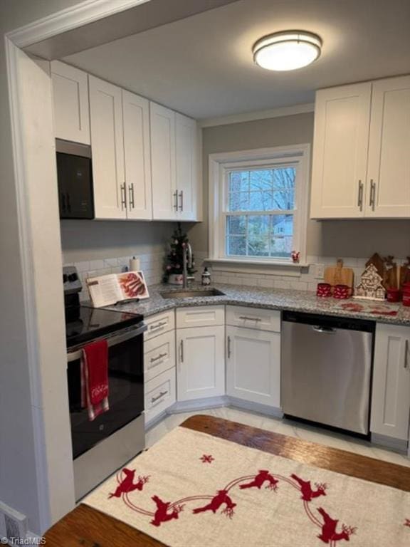 kitchen with white cabinets, stainless steel appliances, light stone countertops, and sink