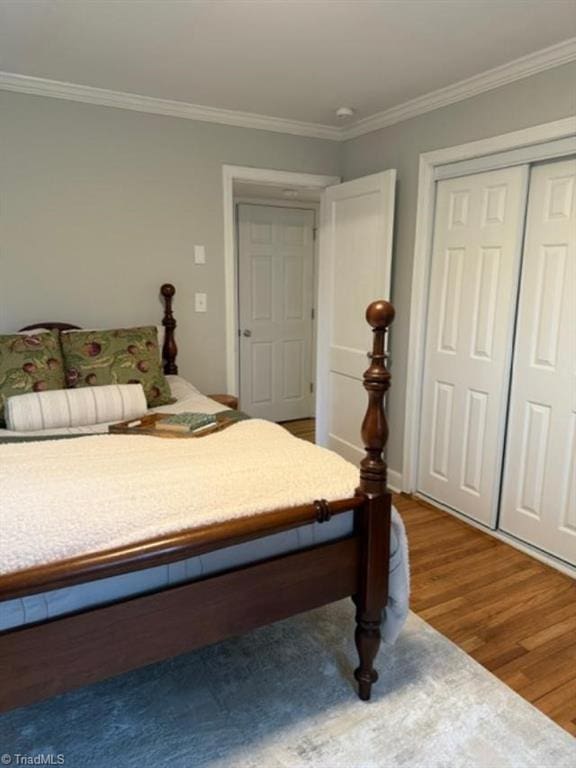 bedroom with hardwood / wood-style flooring, crown molding, and a closet