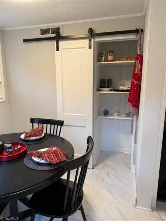 dining space with a barn door and crown molding