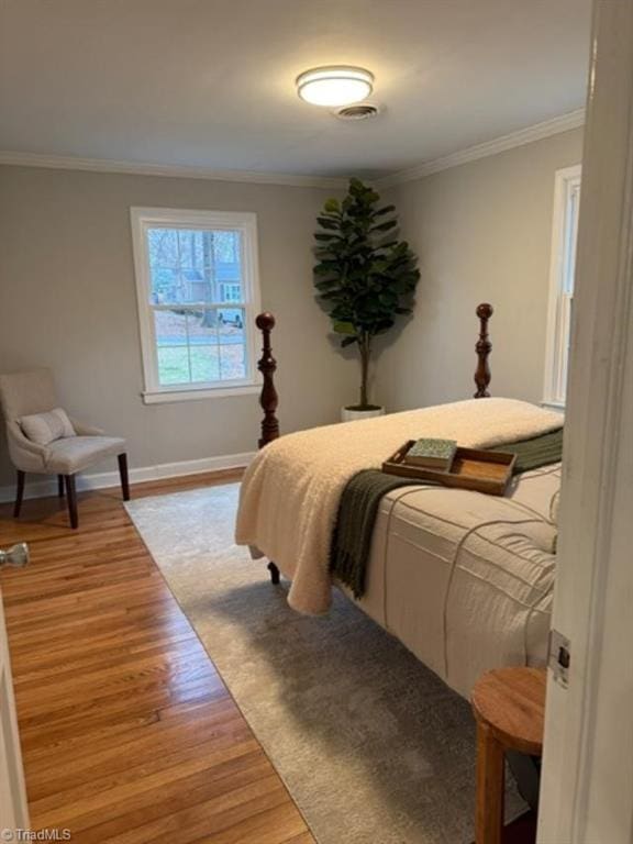 bedroom with ornamental molding and light hardwood / wood-style flooring