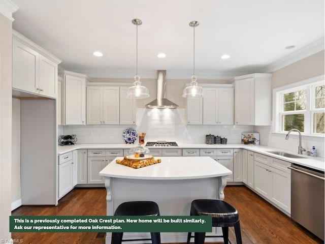 kitchen featuring stainless steel appliances, a sink, white cabinetry, wall chimney exhaust hood, and crown molding