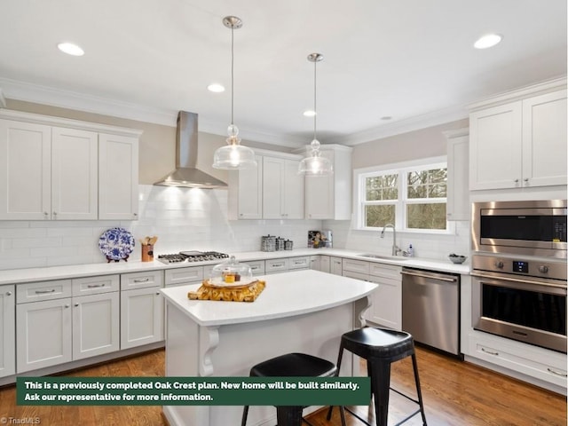 kitchen featuring wall chimney range hood, ornamental molding, stainless steel appliances, and a sink